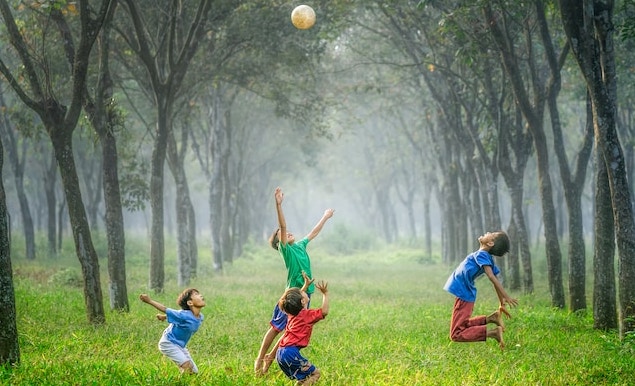 bērni mežā spēlējas ar bumbu