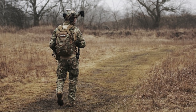 sotilas maastopuvussa kävelee ruohikossa
